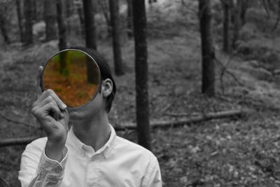 Close-up of man photographing against tree trunk in forest