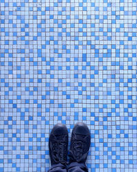 Low section of person standing on vintage blue mosaic tiled floor