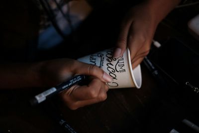 Midsection of woman writing on disposable cup