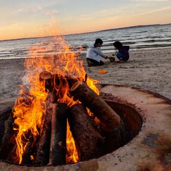 Bonfire on beach against sky during sunset