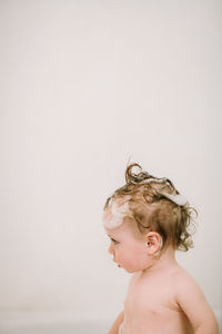 Baby in the bath with soapy hair in profile
