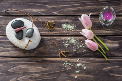 Close-up of pebbles with tea light candle and tulips on table