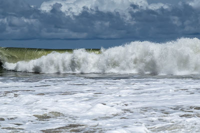 Waves splashing on sea against sky