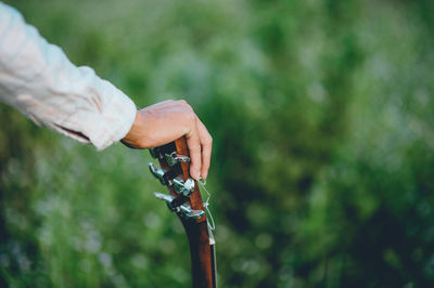 Cropped hand of man holding guitar in park