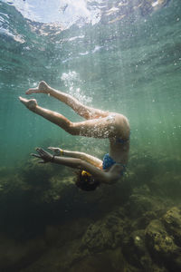 Carefree young woman flipping undersea