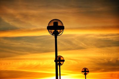 Street light against dramatic sky during sunset