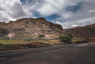 Road amidst rocky mountains against sky