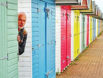 Thoughtful mature man hiding behind beach hut