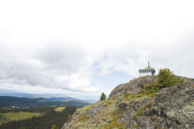 Lighthouse amidst buildings and mountains against sky