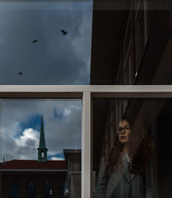 Young woman looking through window