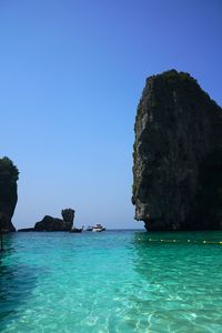 Rock formation in sea against clear blue sky