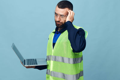 Young man standing against blue background