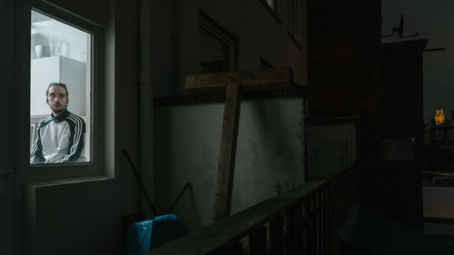 Portrait of man standing by window at home