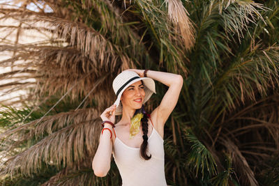 Woman wearing hat while standing against palm trees