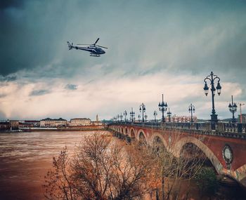 Airplane flying over river against sky