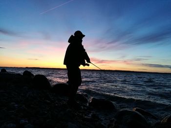 Silhouette man on beach against sky during sunset