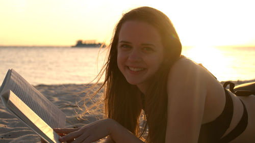 Portrait of young woman using mobile phone at sunset