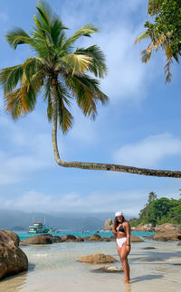 Full length of young woman at beach against sky