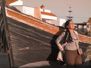 Young woman looking away while standing against built structure