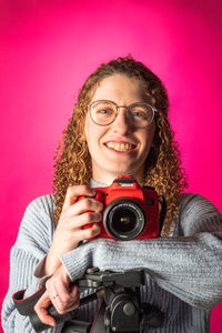 Portrait of young woman holding camera