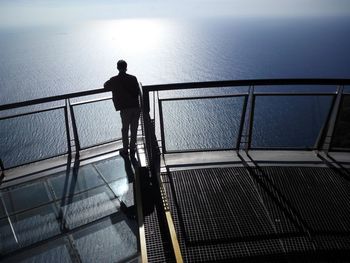 Rear view of man standing at observation point over sea