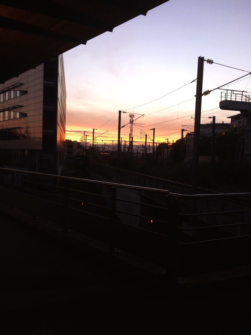 sunset, railroad track, sky, public transportation, orange color, no people, outdoors, city, cable, dark, cloud - sky, power supply, illuminated, development