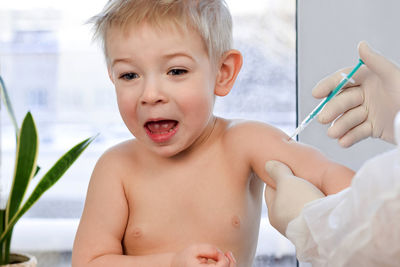 Child kid baby emotions during vaccination. doctor vaccinating little  boy for covid 19 coronavirus