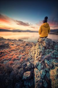 Rear view of man looking at rock against sky