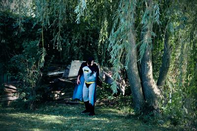 Full length of woman standing amidst trees in forest