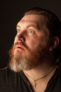 Portrait of man looking away against black background