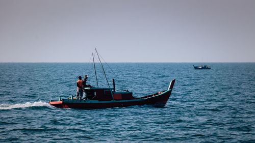 Boat sailing on sea against clear sky