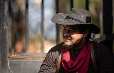 A tobacco pipe is smoked by a cowboy wearing a wide-brimmed hat and a headband.