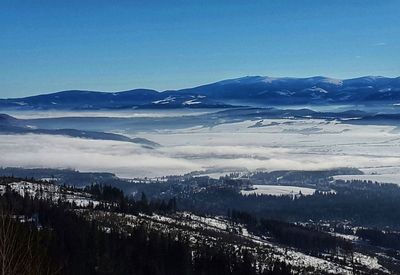 Scenic view of snowcapped mountains against blue sky