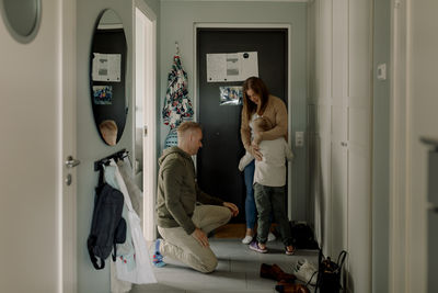 Boy embracing mother by father kneeling in mudroom at home