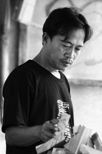 Side view of young man holding a piece of wood