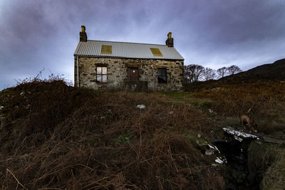 Old abandoned house on field against sky