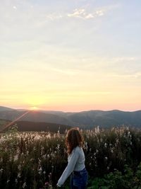 Rear view of woman standing on mountain against sky