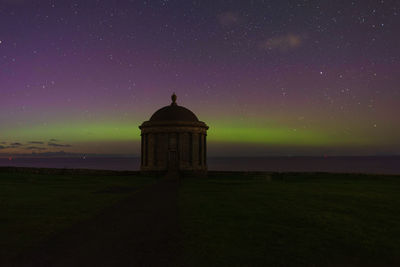 Lighthouse by sea against sky at night