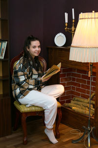 Portrait of young woman sitting on sofa at home