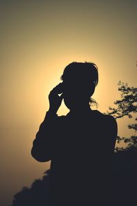 Silhouette woman by tree against sky during sunset