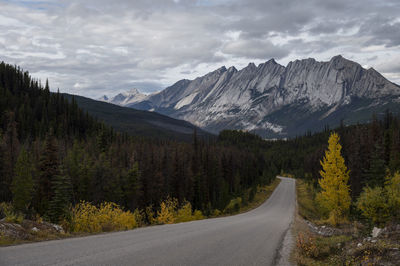 Road amidst trees and mountains against sky