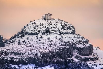 Snow covered land against sky during sunset