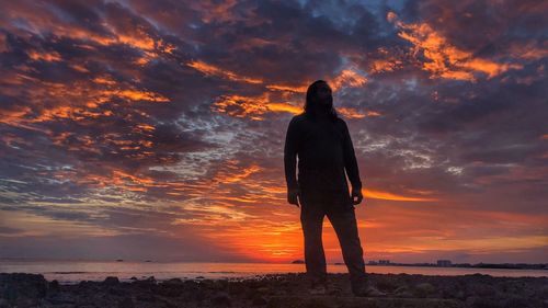 Silhouette man standing on beach during sunset