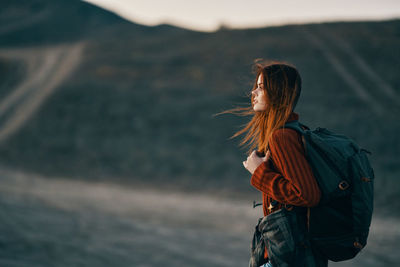 Side view of woman standing at mountain during sunset