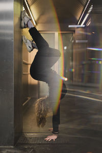 Side view of woman doing handstand at doorway