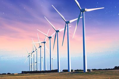 Windmills on field against sky