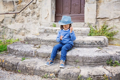 Little handsome baby boy sitting on ancient stone stairs