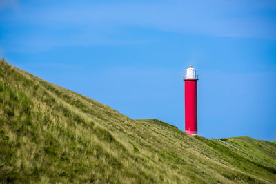 Minimalist photo of a lighthouse by road amidst hills against sky in julianadorp, the netherlands