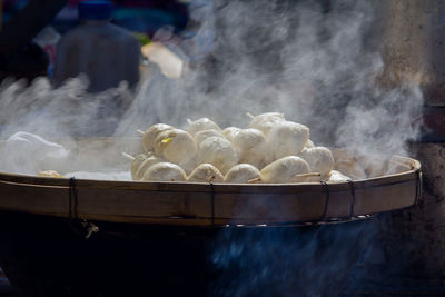 Close-up of steam emitting from dumplings in container