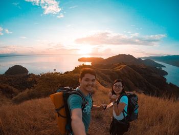 Portrait of smiling young couple standing against sky during sunset